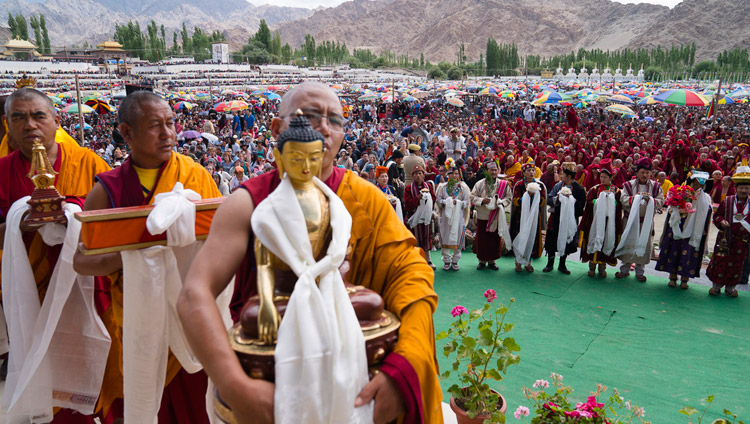 Members of the community carrying offerings pass in front of His Holiness the Dalai Lama while local artists perform behind them during the Long-Life Offering ceremony in Leh, Ladakh, J&K, India on July 30, 2017. Photo by Tenzin Choejor/OHHDL